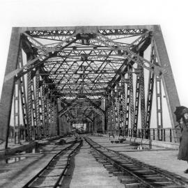 Tom Ugly's Bridge under construction, view looking down length of bridge with woman standing at the right, ca. later 1920s