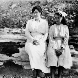 Woman and girl sitting on rock at Jibbon Beach, ca. 1918