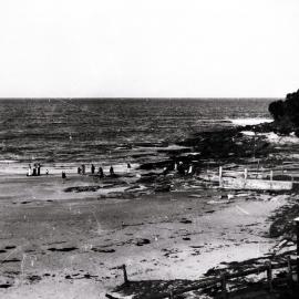 People on rocks and at water's edge, Cronulla Beach, with pool to right