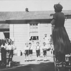 Teacher supervising pupils in the playground at Sutherland Public School, ca. 1930s-1940s